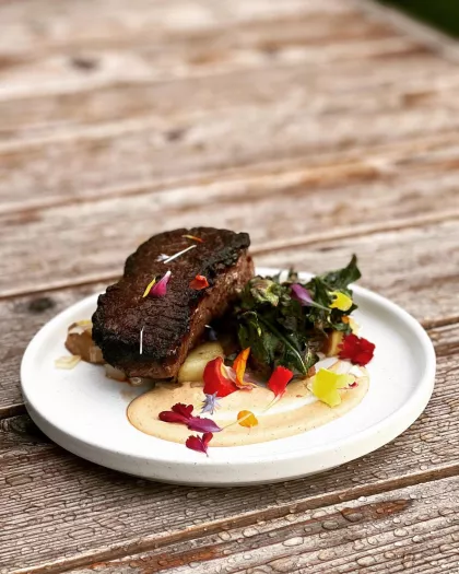 Bison New York strip with sweet potato hash, charred tomato hollandaise and grilled dandelion greens at Owamni