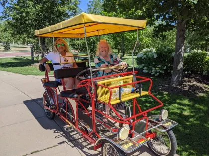 Two women on a four-wheel pedal bike at Minnehaha Falls