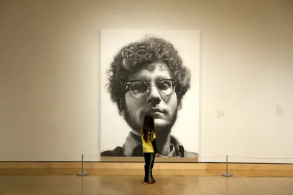 A girl stands in front of Chuck Close's "Frank" piece at the Minneapolis Institute of Art