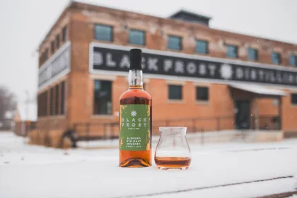 A bottle of Black Frost Distilling's Blended Rye Malt Whiskey in the snow outside the distillery