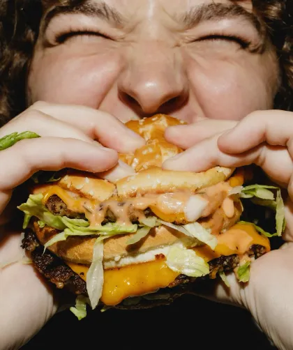 A customer bites into a burger at Francis Burger Joint