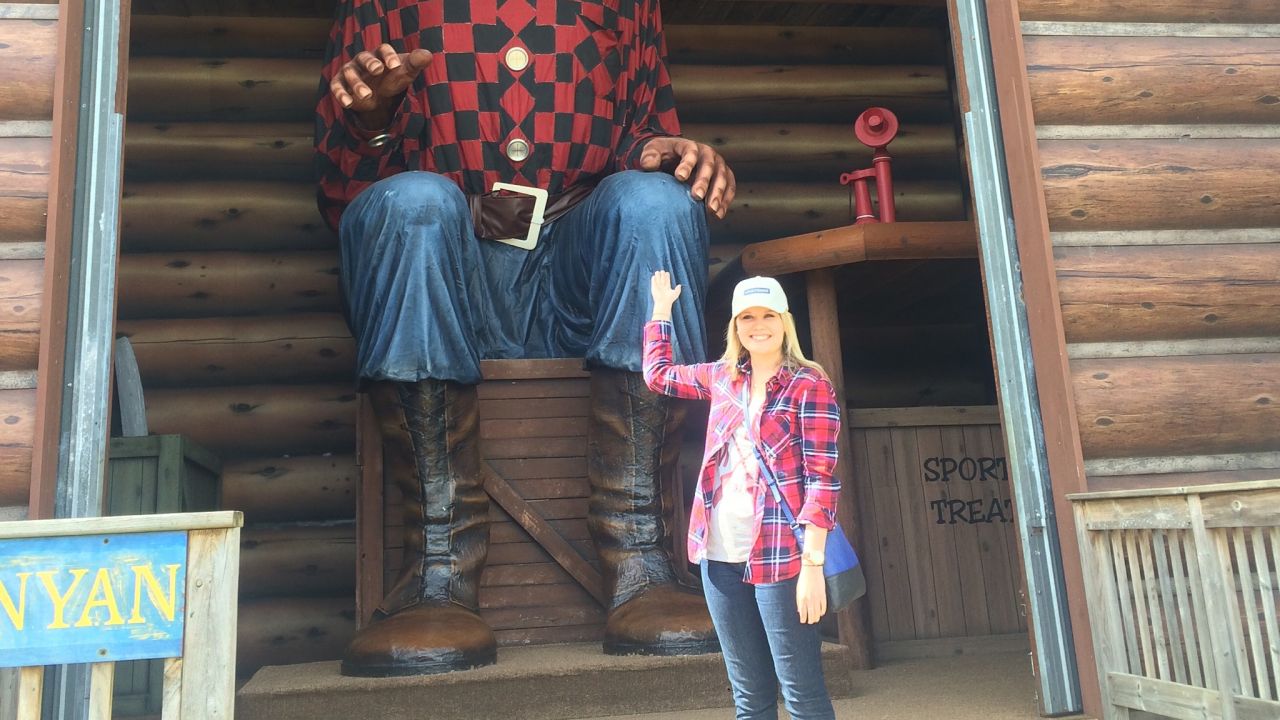 Mujer posando con la estatua de Paul Bunyan en Paul Bunyan Land