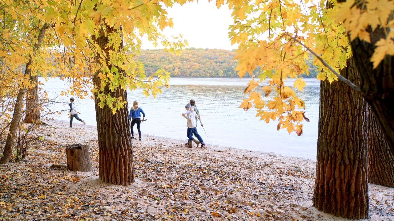 Familia camina a lo largo del río en otoño