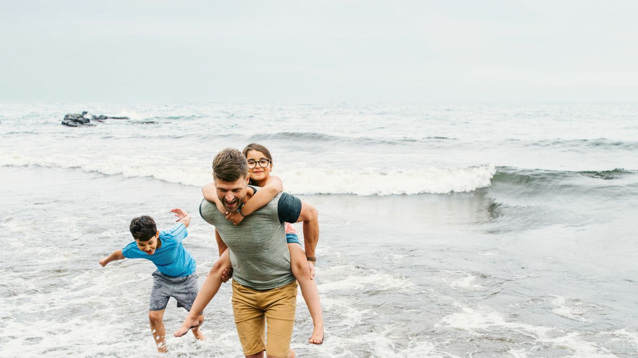 Father and kids play on the shore of Lake Superior in Grand Marais