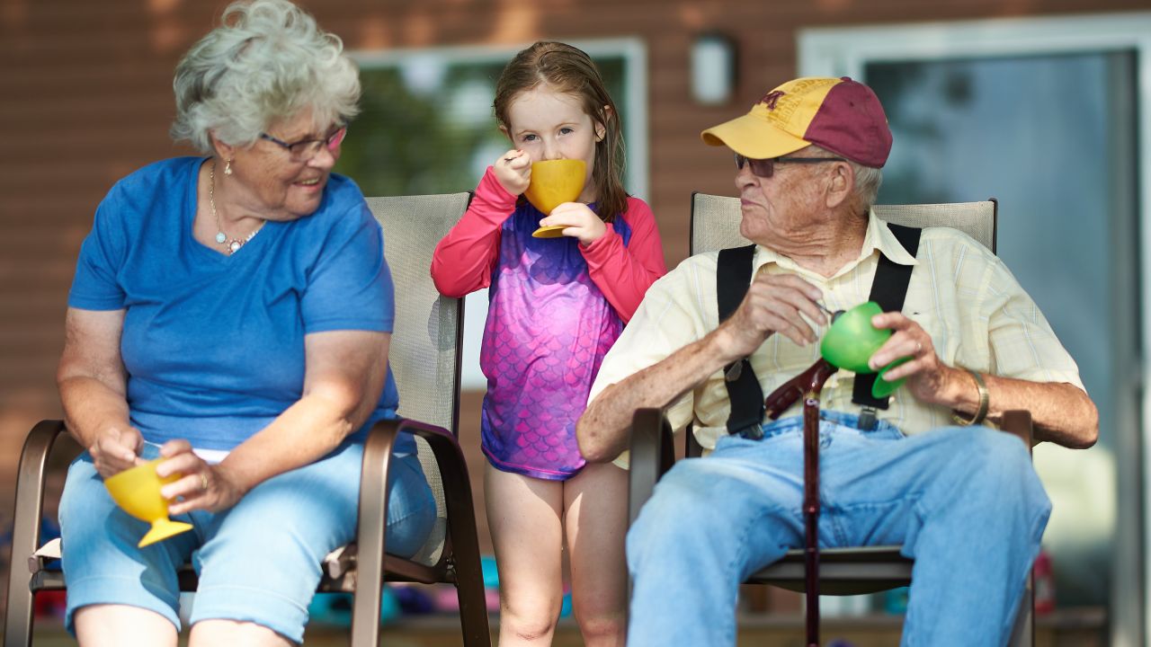 Grandparents and granddaughter eat ice cream outside