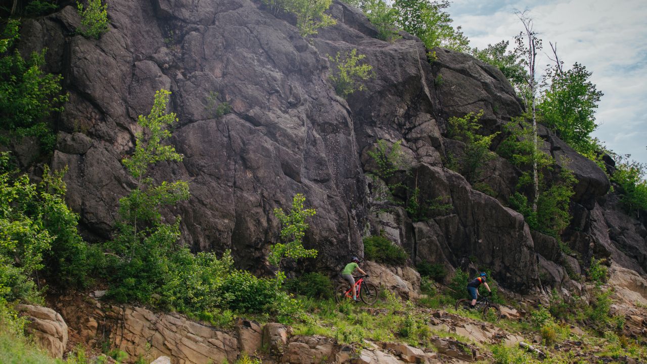 Two mountain bikers riding near rock face in Duluth