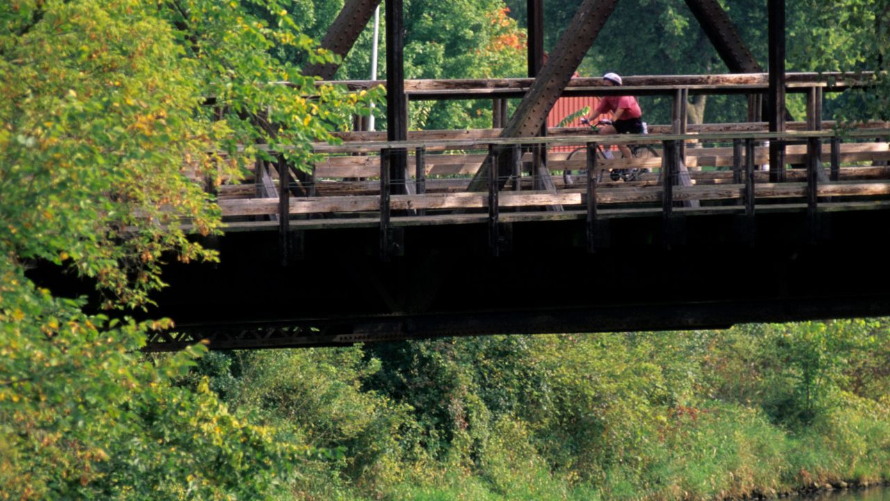 Bicyclist rides on a bridge above the Root River