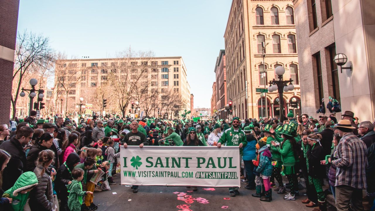 St. Patrick's Day parade-goers holding a Visit Saint Paul banner