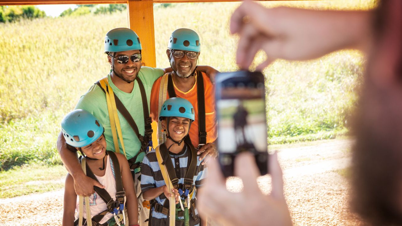 Family poses for photo in zip lining gear