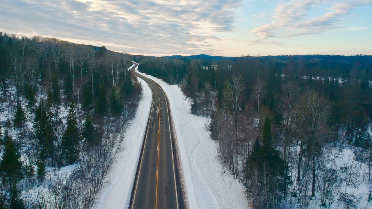Winding road cuts through the a wintery forest scene