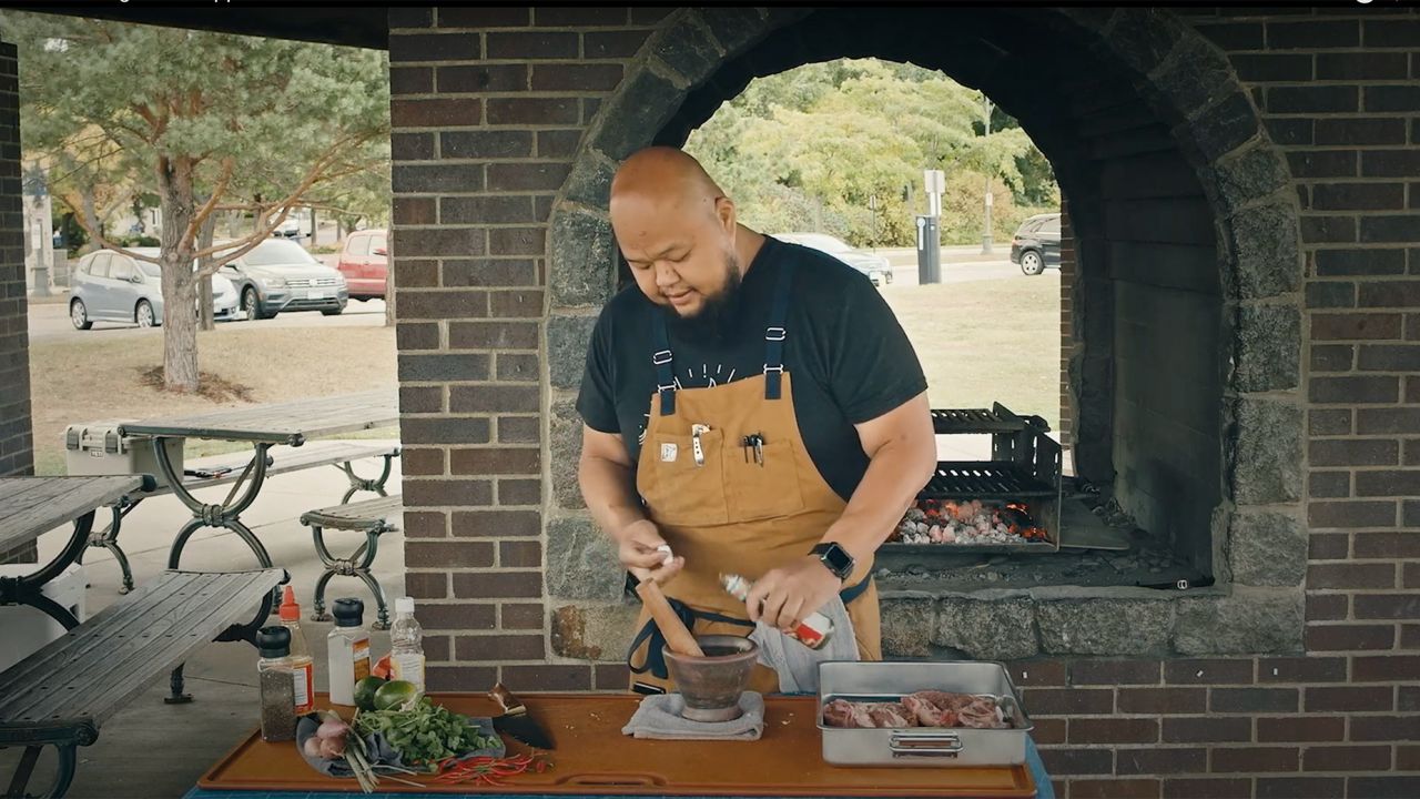 Chef Yia Vang prepares Tiger Bite Sauce to be paired with Grilled Pork Coppa over an open flame at Boom Island Park