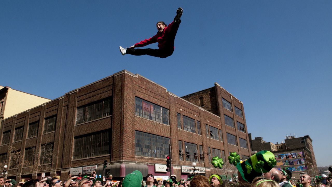 A man doing a split high above onlookers during the St. Patrick's Day Parade in St. Paul
