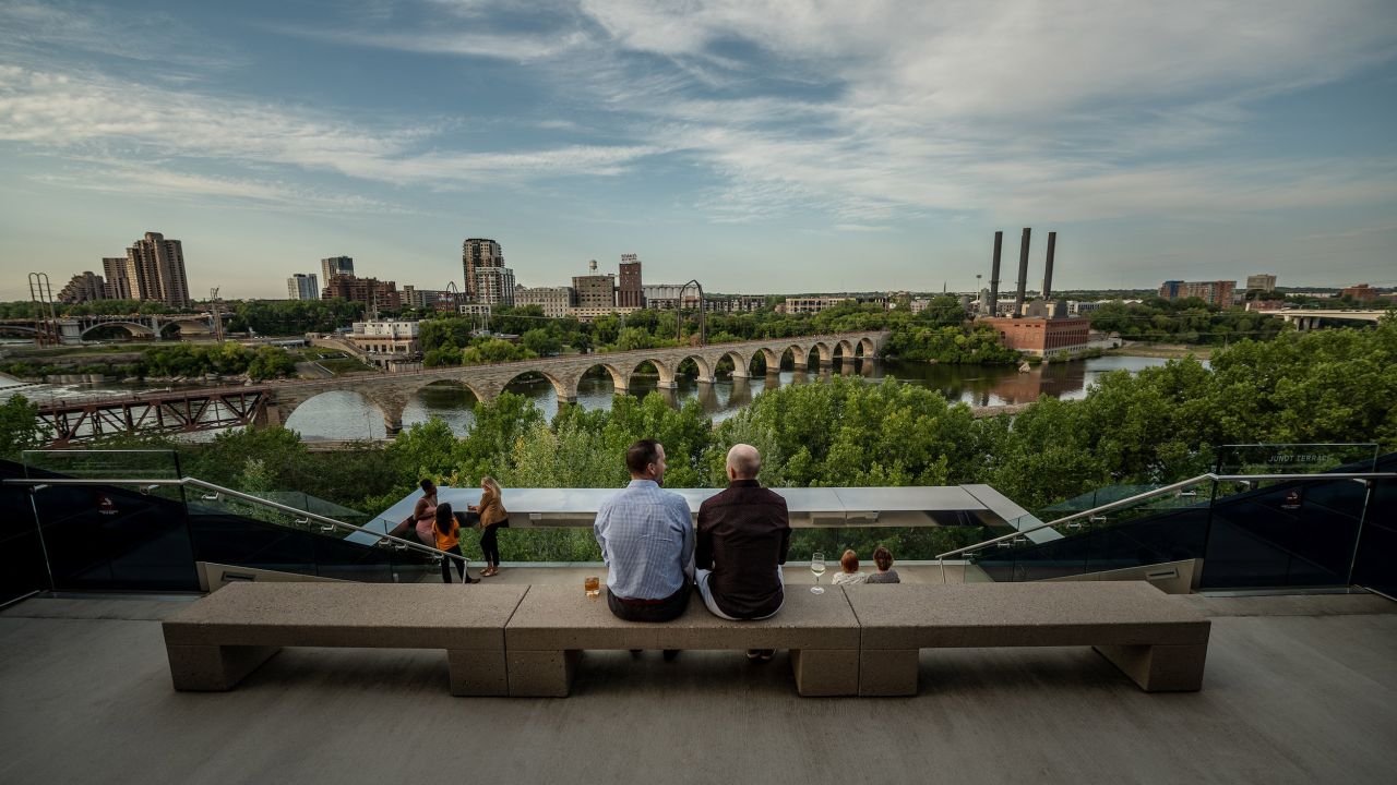 A couple men look at the Minneapolis skyline from the top of the Guthrie Theater