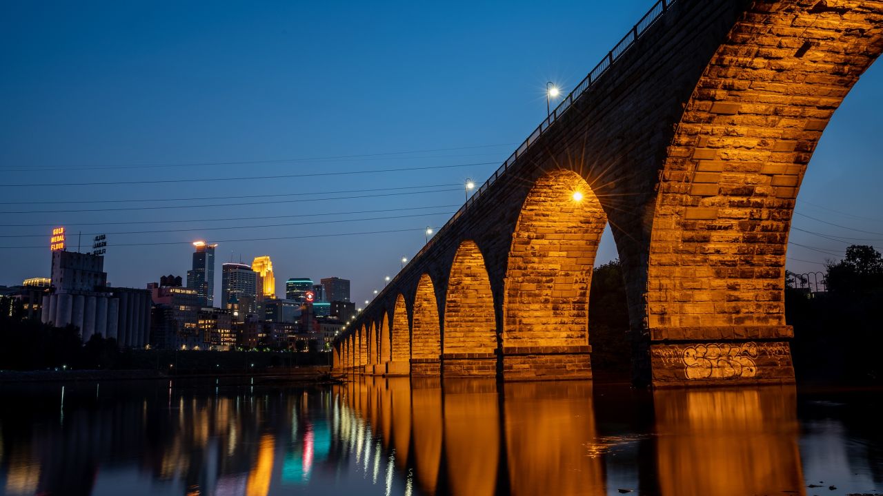 A nighttime landscape shot of Saint Anthony Main and the Stone Arch Bridge