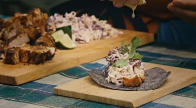 A swordfish taco with blue corn tortilla wrapper, slaw and cilantro garnish