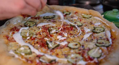 Hayden Haas drizzles ranch on his Dill Pickle Pizza