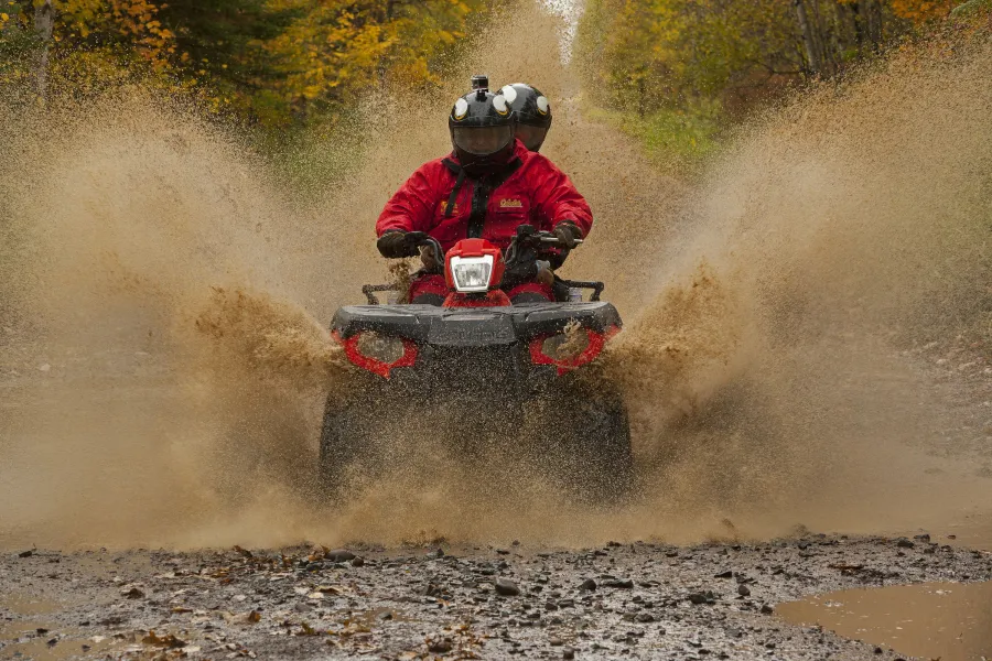 ATV riders go through a mud puddle