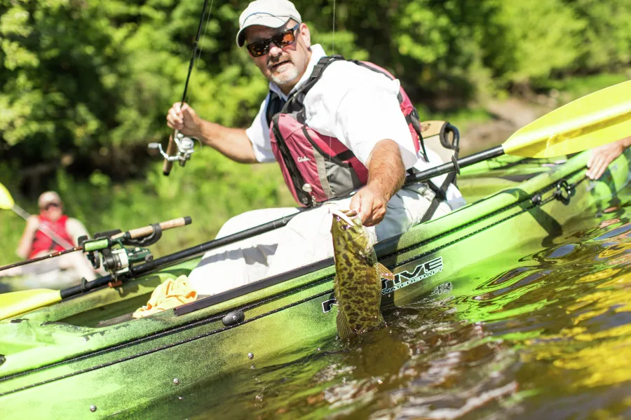 Man in kayak pulls a smallmouth bass 