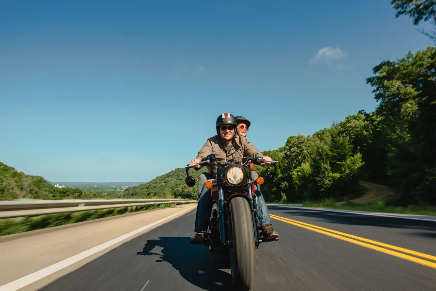 Red wing smiling couple driving motorcycle