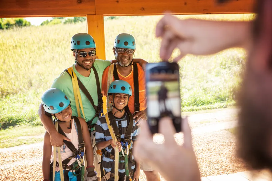Family poses for photo in zip lining gear