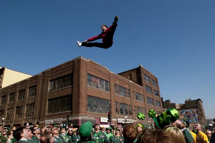 A man doing a split high above onlookers during the St. Patrick's Day Parade in St. Paul