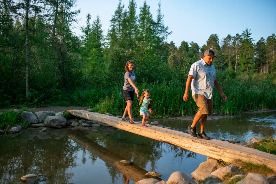 A family crossing a log bridge in Itasca State Park, Headwaters of the Mississippi River