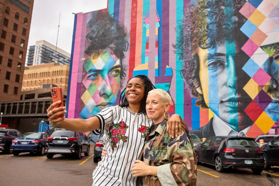 A couple takes their picture in front of the Bob Dylan mural in downtown Minneapolis