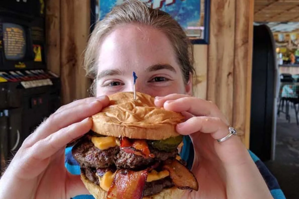 woman holding up a bacon cheeseburger