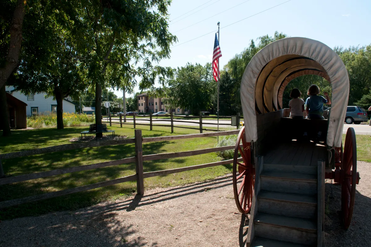 Kids playing in a covered wagon at the Laura Ingalls Wilder Museum