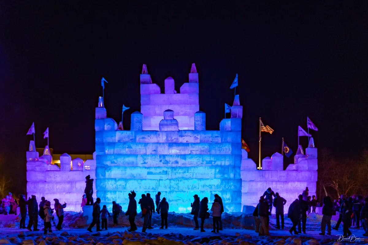 An Ice Palace is illuminated in blue and purple at night