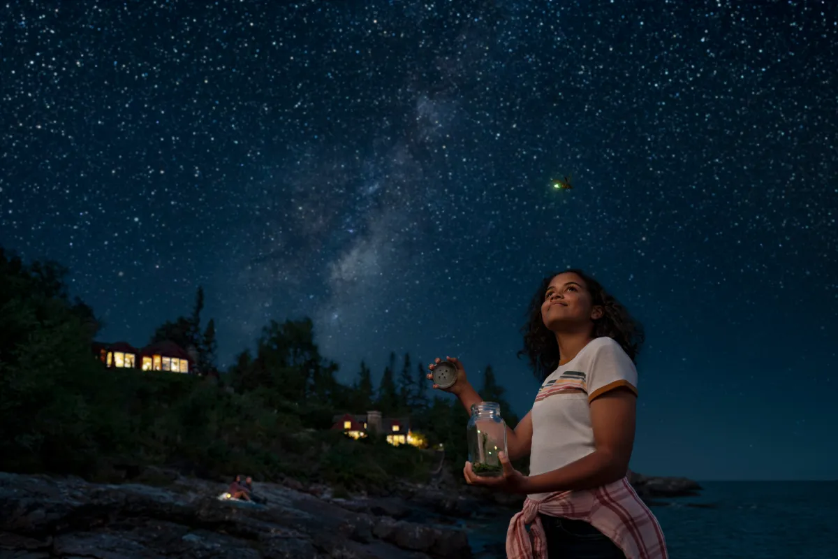 A girl catching fireflies in front of North Shore cabins off Lake Superior