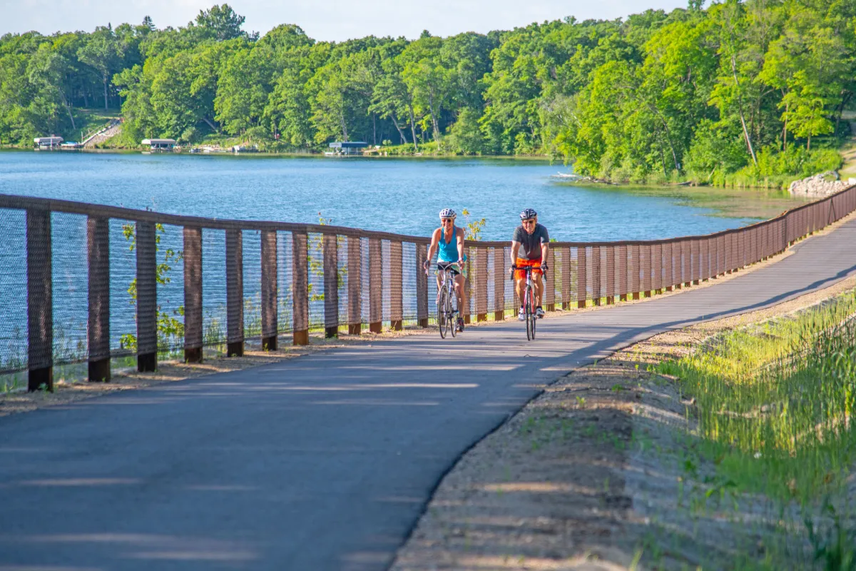 A couple bikers pass Acorn Lake on the Heartland State Trail