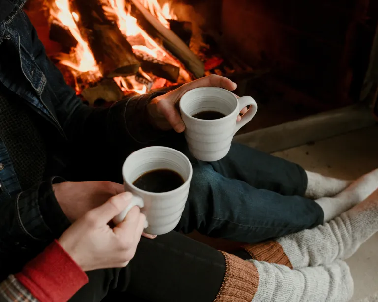 Couple drinking coffee by the fireplace