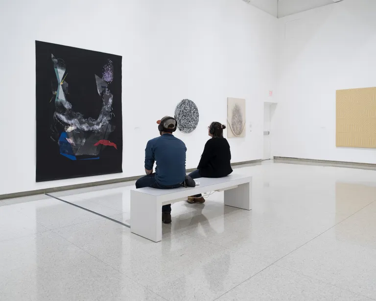 Two people sitting on a bench to view a painting at the Walker Art Center