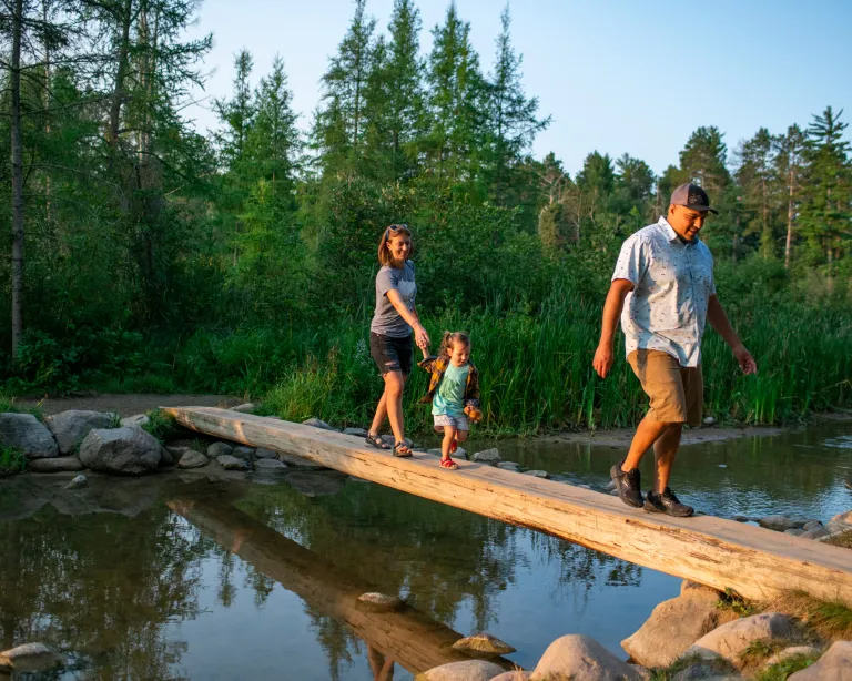 A family crossing a log bridge in Itasca State Park, Headwaters of the Mississippi River