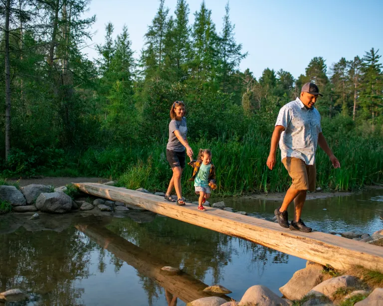 A family crossing a log bridge in Itasca State Park, Headwaters of the Mississippi River